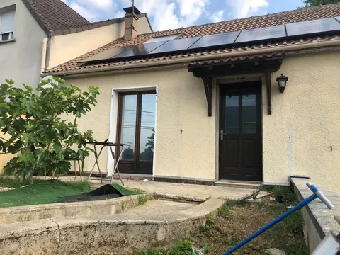 Maison individuelle avec une rangée de panneaux solaires noirs sur un toit en tuiles