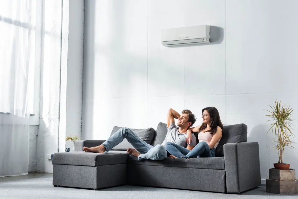 Couple détendu dans un salon lumineux équipé d’une climatisation murale réversible